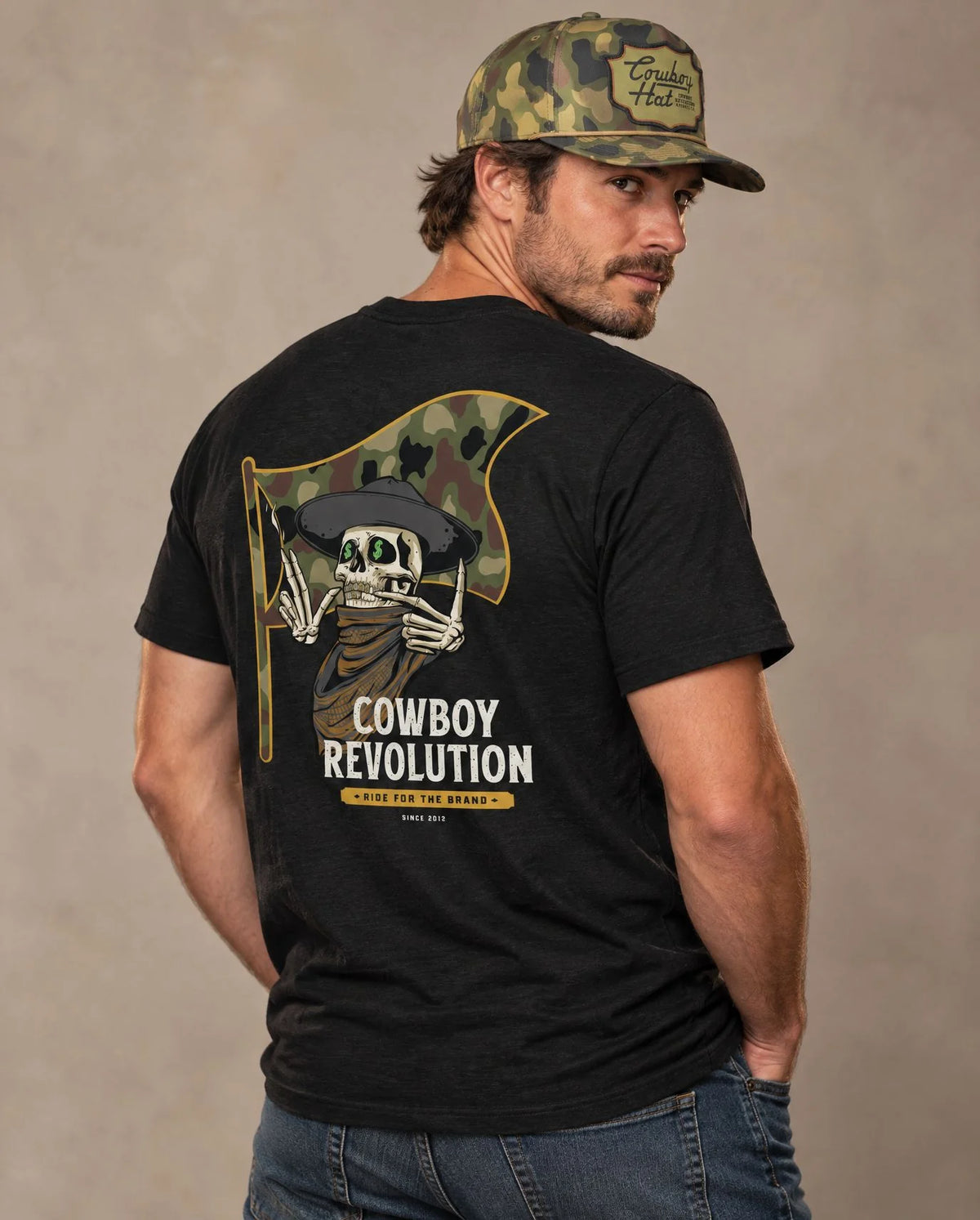 Male model in Cowboy Code No. 7 Ride for the Brand tee, Solid Black and Woodland Camo rope hat, Cowboy Revolution